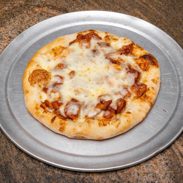 A small, round pizza with melted cheese and chicken pieces on a metal tray.
