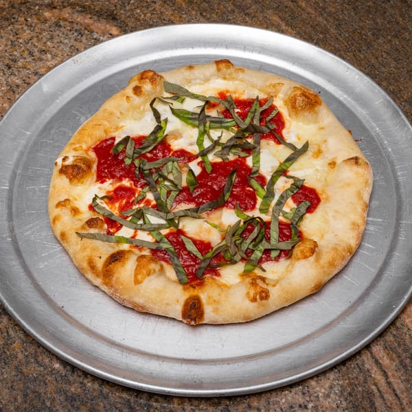 A freshly baked Margherita pizza with tomato sauce, mozzarella, and basil on a metal tray.